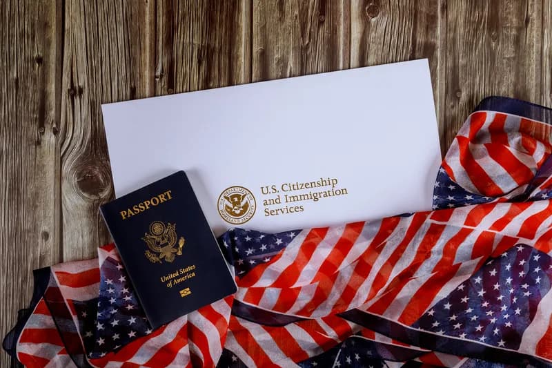 A US passport and a certificate of naturalization arranged on an American flag.
