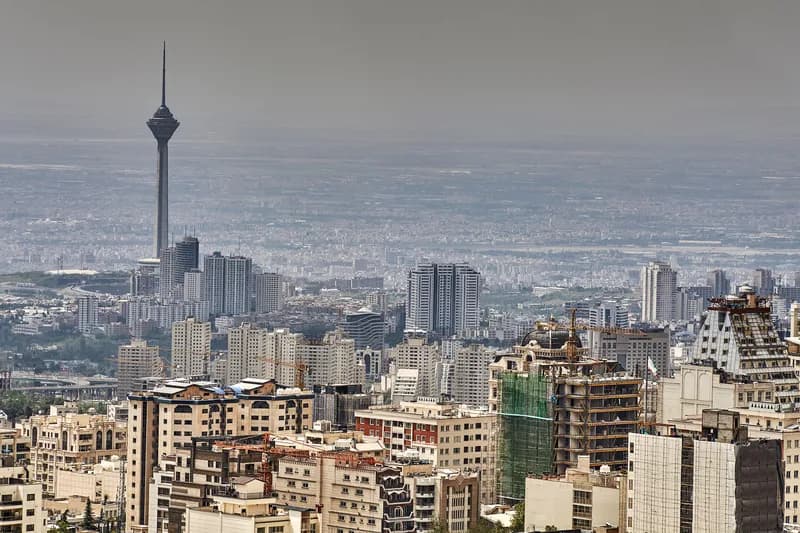 The Tehran skyline, with the Milad Tower rising above the city and the Alborz mountains behind.