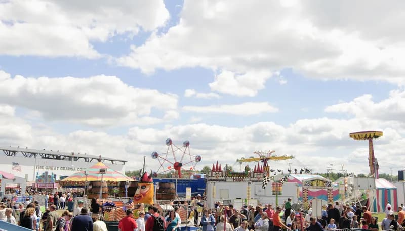 Crowds on the midway at a county fairground under a wide sky